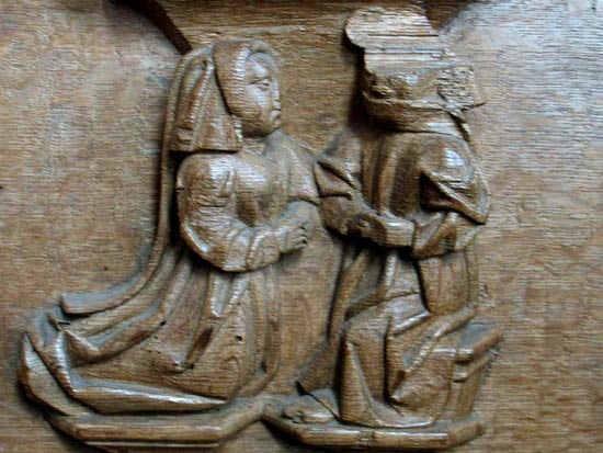 knielende vrouw biecht haar zonden. Houtsnijwerk, 15de eeuw. Bolsward, Martinikerk, koorgestoelte.