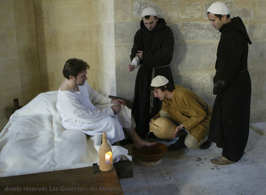 Hospitaalbroeders wassen de voeten van een zieke. Reconstructie door Les guerriers du Moyen-Age